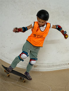 Skate Academy leerling, jong kind. Skateboard van miniramp af.